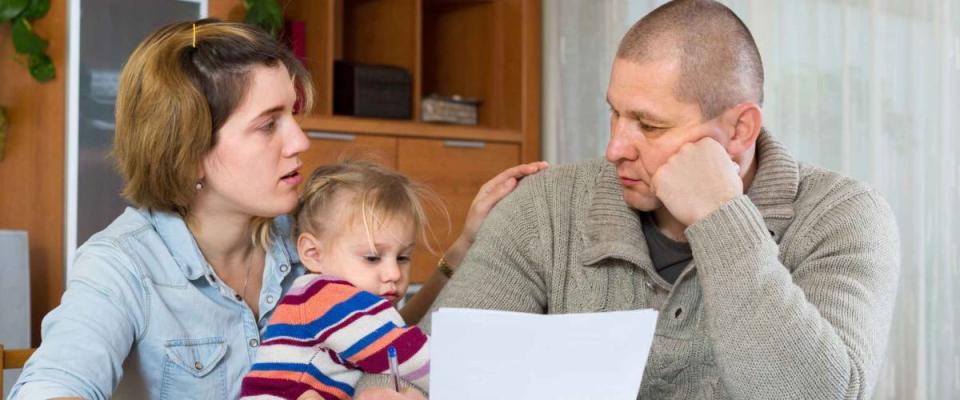 Worried family with child sitting with financial documents at home