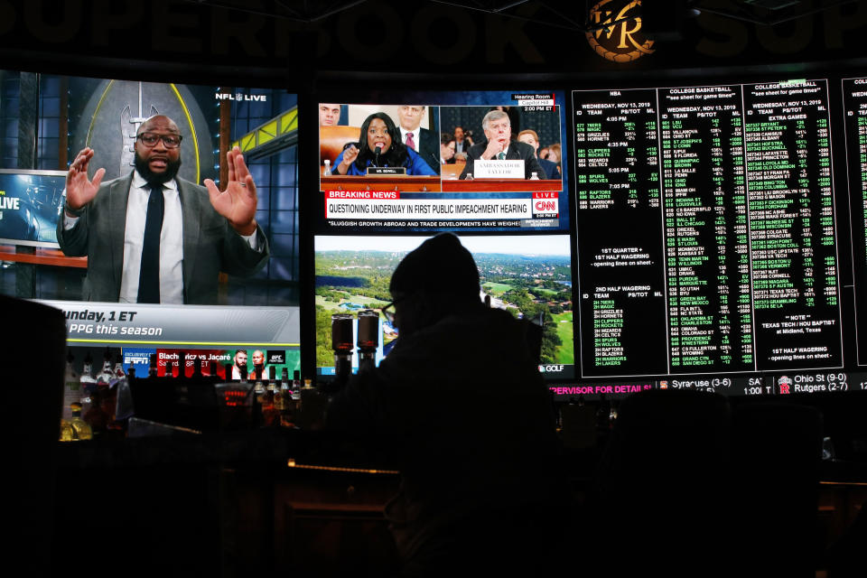 The first public impeachment hearing of President Donald Trump plays on a screen at the Superbook sports book inside the Westgate casino-hotel Wednesday, Nov. 13, 2019, in Las Vegas. (AP Photo/John Locher)