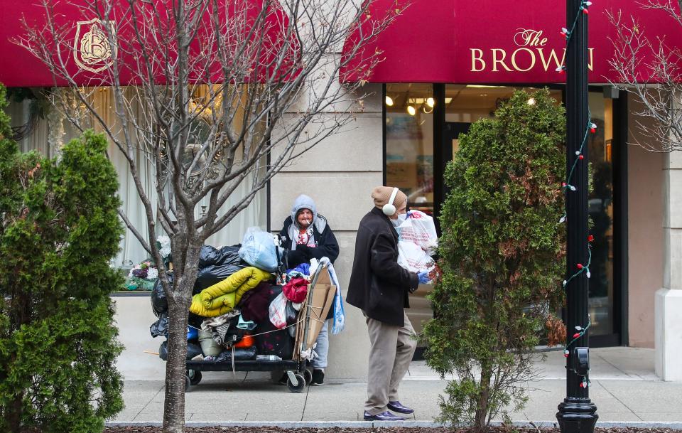 Sharon McLarney, 66, watches as a woman carries two shopping bags from CVS outside The Brown hotel on 4th Street recently. McLarney said she's been homeless for the past 15 days and pushes her belongings on a cart. She was staying at Hotel Louisville nearby at Broadway and Second Street. Dec. 5, 2023