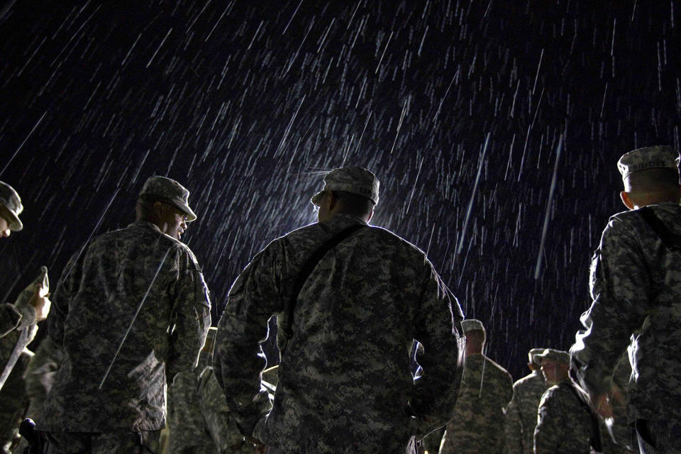 <p>1st Lt. Nikesh Kapadia, 24, center, of Queens, N.Y., with the U.S. Army’s 4th Brigade Combat Team, 101st Airborne Division out of Fort Campbell, Ky., stands in the rain while waiting to go through customs at the Transit Center in Manas, Kyrgyzstan, on the way home after completing a deployment in Afghanistan on Aug. 10, 2011. The 4th Brigade Combat Team, 101st Airborne Division is returning home after a year in Afghanistan as the last brigade to deploy as part of President Obama’s 30,000 troop surge. (AP Photo/David Goldman) </p>