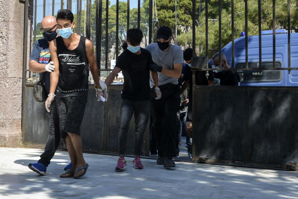 Suspects, all from Afghanistan escorted by plain clothes policemen and wearing face masks, arrive at a court in Mytilene, the capital of the northeastern Aegean island of Lesbos, Greece, Wednesday, Sept. 16, 2020. The government says the fires in Moria refugee camp were set deliberately by the Afghan migrants protesting a coronavirus lockdown, and authorities on Tuesday announced the arrests of six suspect, include two 17-year-olds, in the case. (AP Photo/Panagiotis Balaskas)