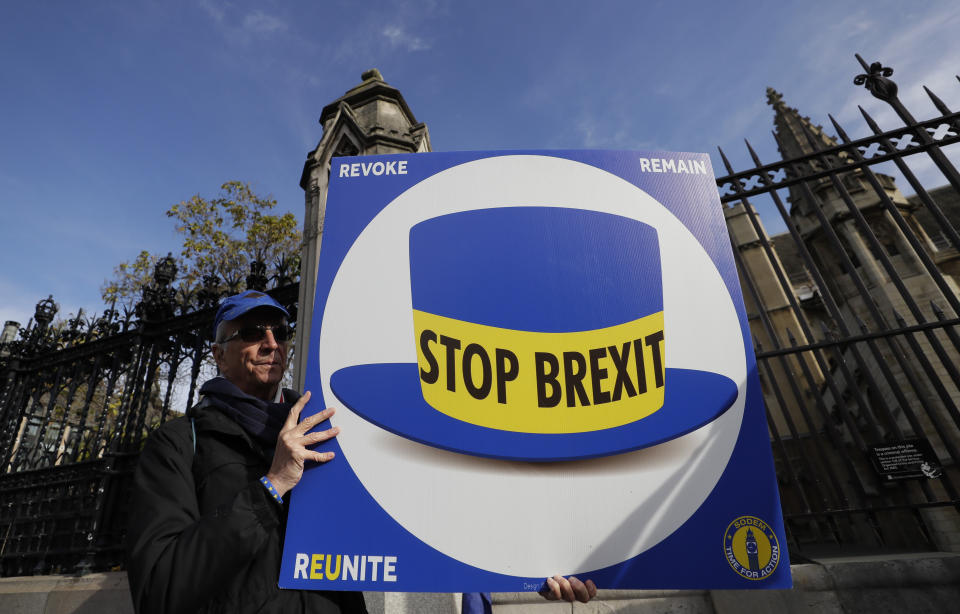 An anti-Brexit demonstrator holds up a banner outside Parliament in London, Wednesday, Oct. 30, 2019. Britons will be heading out to vote in the dark days of December after the House of Commons on Tuesday backed an early national vote that could break the country's political impasse over Brexit — or turn out to be merely a temporary distraction. (AP Photo/Kirsty Wigglesworth)
