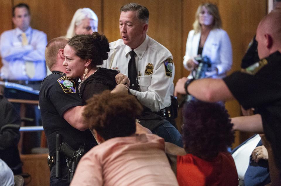 Protester Ashley Popio is removed from a N.C. Historical Commission meeting at the N.C. State Archives in Raleigh after she made an outburst while commission members were making recommendations on what to do with three Confederate monuments at the N.C. State Capitol grounds, Wednesday, Aug. 22, 2018. (Travis Long/The News & Observer via AP)
