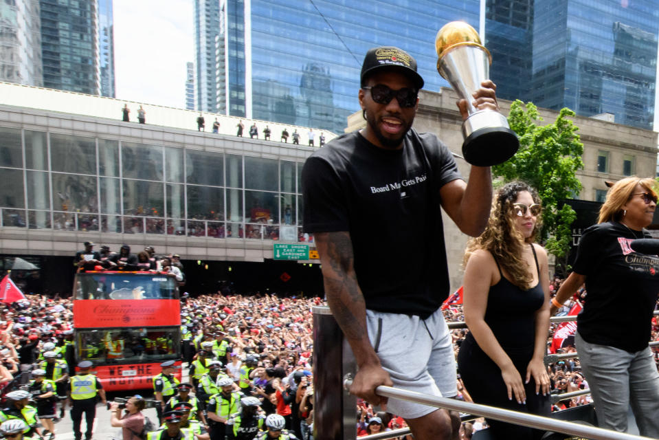 NBA Finals MVP Kawhi Leonard raises the trophy on top of the bus during the Toronto Raptors Championship parade. Source: Getty