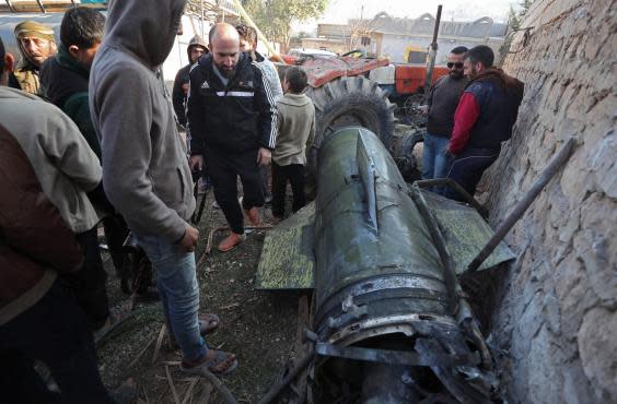 Civilians gather next to a fragment of a ground-to-ground missile fired by Syrian regime forces (AFP via Getty Images)