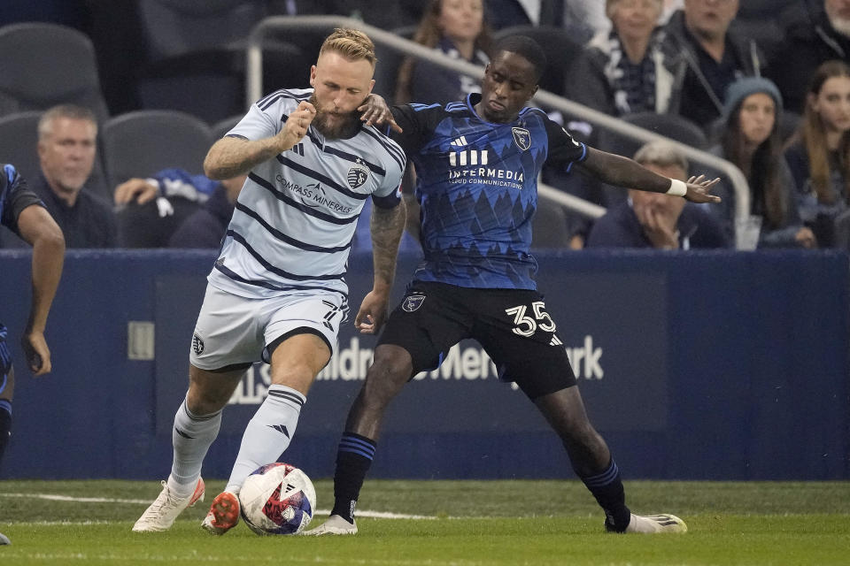 Sporting Kansas City forward Johnny Russell (7) and San Jose Earthquakes midfielder Jamiro Monteiro (35) battle for the ball during the first half of an MLS soccer wild-card playoff match Wednesday, Oct. 25, 2023, in Kansas City, Kan. (AP Photo/Charlie Riedel)