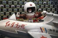 A child wearing a face mask to help curb the spread of the coronavirus poses for a souvenir photo near a toy plane inside a shopping mall in Beijing, Monday, Jan. 18, 2021. A Chinese province grappling with a spike in coronavirus cases is reinstating tight restrictions on weddings, funerals and other family gatherings, threatening violators with criminal charges. (AP Photo/Andy Wong)