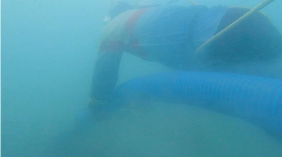Joko holds the vacuum tube in place at the seabed