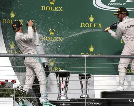 Formula One F1 - U.S. Grand Prix - Circuit of the Americas, Austin, Texas, U.S., 23/10/16. Race winning Mercedes driver Lewis Hamilton of Britain and second placed finisher and teammate Nico Rosberg of Germany (L) douse an attendee of the victory ceremony with champagne. REUTERS/Adrees Latif