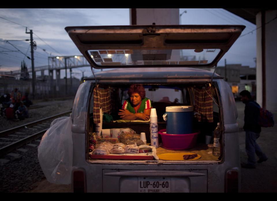 In this May 17, 2012 photo, Maria Campos, waits for customers to sell them food from her car, parked near the train tracks where migrants, mostly from Honduras, wait for trains going north, in Lecheria on the outskirts of Mexico City. While the number of Mexicans heading to the U.S. has dropped dramatically, a surge of Central American migrants is making the 1,000-mile northbound journey this year, fueled in large part by the rising violence brought by the spread of Mexican drug cartels. (AP Photo/Alexandre Meneghini)
