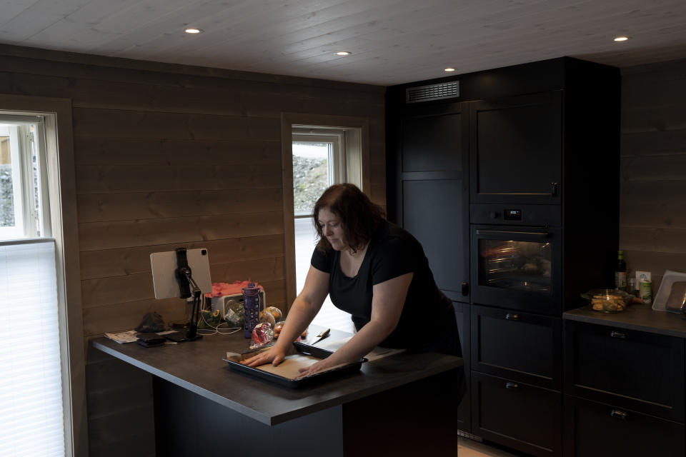 Garrett Fisher's wife, Anne, prepares a meal at their rented house in Voss, Norway, on Aug. 3, 2022. She accompanies him everywhere he goes while on his mission to photograph all the remaining glaciers that are not in the polar regions. (AP Photo/Bram Janssen)