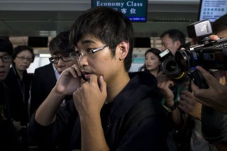 Hong Kong Federation of Students leader Alex Chow talks on his mobile phone after being refused to board the plane at the Hong Kong International Airport November 15, 2014. REUTERS/Tyrone Siu
