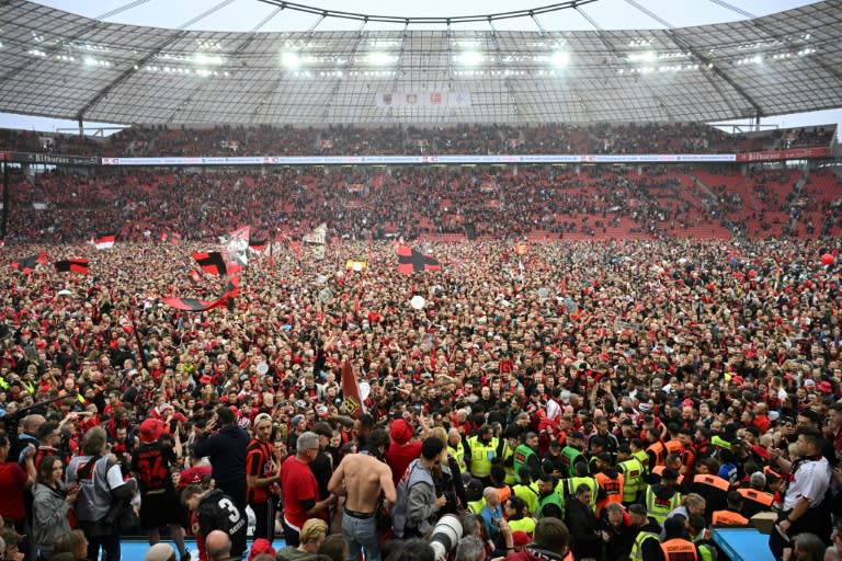 Una multitud de aficionados del Leverkusen celebran sobre el césped el título de la Bundesliga tras la victoria ante el Werder Bremen, en Leverkusen, el 14 de abril de 2024 (INA FASSBENDER)