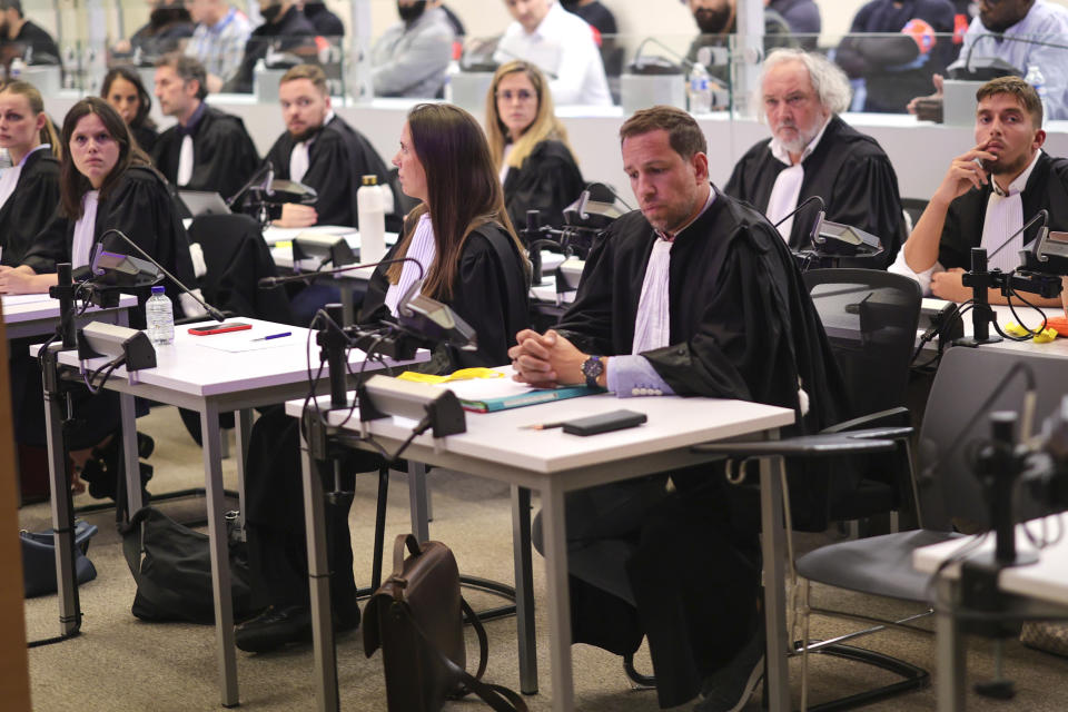 Lawyers sit at tables in front of a specially designed glass box, holding the accused, in the courtroom during the start of the Brussels terrorist attack trial verdict in the Justitia building in Brussels, Tuesday, July 25, 2023. A jury is expected to render its verdict Tuesday over Belgium's deadliest peacetime attack. The suicide bombings at the Brussels airport and a busy subway station in 2016 killed 32 people in a wave of attacks in Europe claimed by the Islamic State group. (Olivier Matthys, Pool Photo via AP)