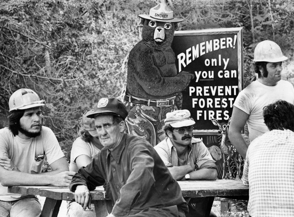 Smokey the Bear, the symbol of the nation's fire prevention efforts, stands watch at Togue Pond headquarters behind new crew awaiting transportation to fire lines of a forest fire in Millnocket, Maine, in 1977. (Photo: William Ryerson/The Boston Globe via Getty Images)