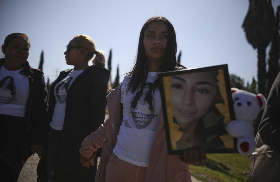 Marbella Valdez's friends, wearing T-shirts featuring her portrait, hold hands and pray during her burial at a cemetery in Tijuana, Mexico, Friday, Feb. 14, 2020. When the law student’s body was found at a garbage dump in Tijuana, the man who was obsessed with her demanded police solve the case, attended her funeral, and a week later was arrested and charged with her murder. The man, identified by Mexican rules only by his first name, Juan, has insisted on his innocence. (AP Photo/Emilio Espejel)