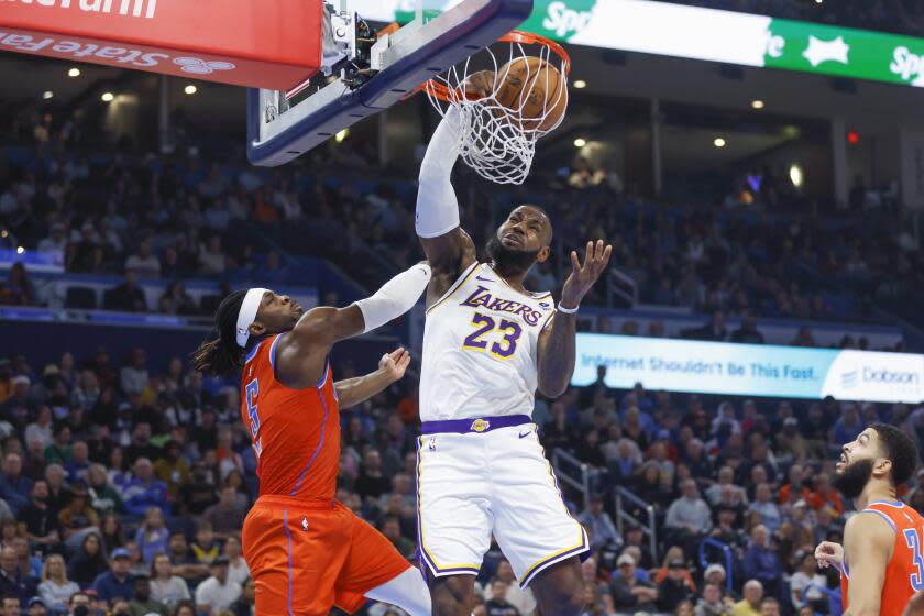 Los Angeles Lakers forward LeBron James (23) dunks against Oklahoma City Thunder guard Luguentz Dort, left, as forward Kenrich Williams, right, watches during the first half of an NBA basketball game Saturday, Dec. 23, 2023, in Oklahoma City. (AP Photo/Nate Billings)