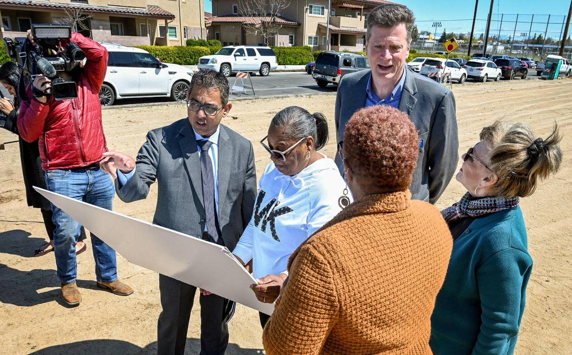 Fresno Councilmember Miguel Arias, at left-center, looks over renderings of new homes with representatives from Self-Help Enterprises, the Fresno Redevelopment Successor Agency, and the Golden West Side Planning Committee, after announcing the beginning of construction of a single-family affordable housing project on an empty lot near Edison High School at Walnut and Florence avenues in west Fresno on April 4, 2023.