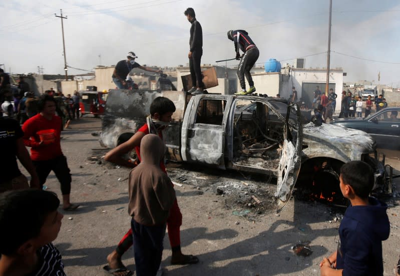 Protesters step on a military vehicle of Iraqi security forces after burning it, during ongoing anti-government protests in Basra