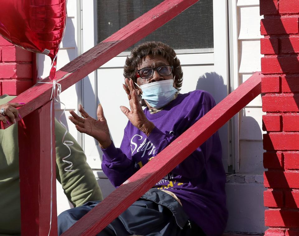 Earlene Fullwood claps as cars pass and drivers honk their horns Sunday, Feb. 11, 2024, during a drive-by 100th birthday celebration in front of her East Summit Street home in Alliance.