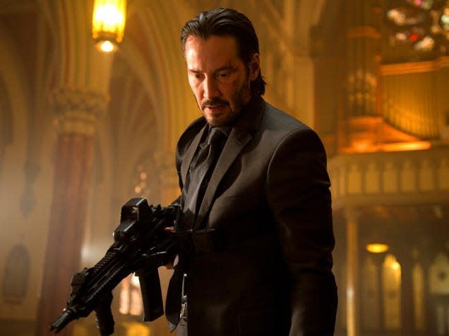 Keanu Reeves as John Wick holding a rifle in the Russian church.