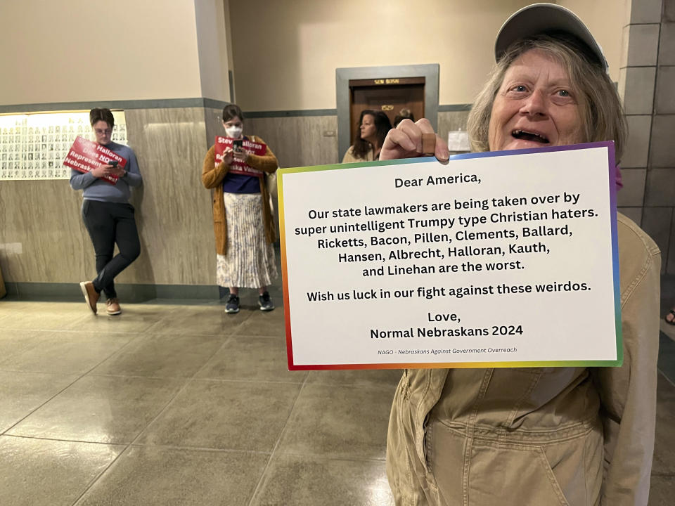 Donna Roller, 72, holds up a sign and stands with others Thursday, March 28, 2024, who were protesting in the Nebraska State Capitol in Lincoln, Neb., outside a hearing on a measure that would censure Republican state Sen. Steve Halloran. (AP Photo/Margery Beck)