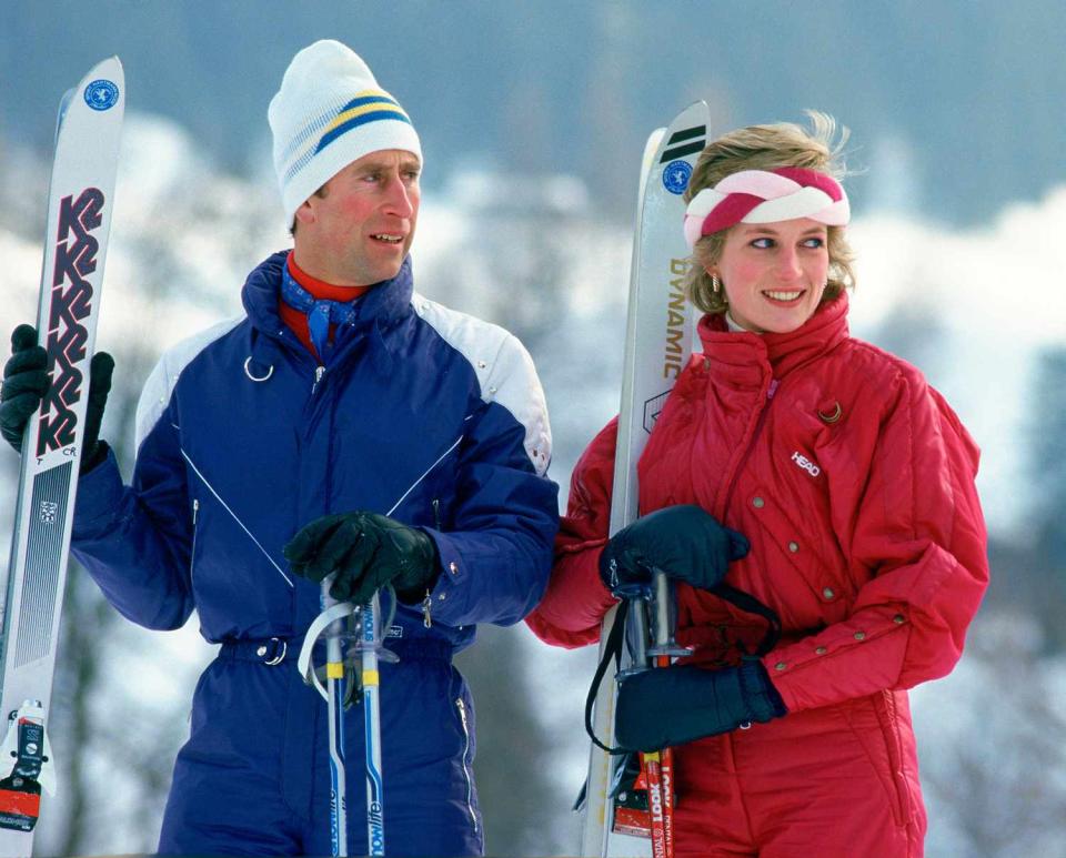 Prince Charles With Princess Diana On A Ski-ing Holiday Together. The Princess Is Wearing A Red "head" Ski Suit And A Headband And She Is Holding A Pair Of "dynamic" Skis. The Prince Is Wearing A Blue Ski Suit And Carrying A Pair Of "k2" Skis