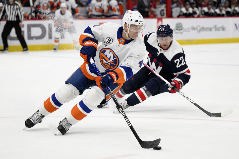 New York Islanders defenseman Andy Greene (4) skates with the puck in front of Washington Capitals left wing Johan Larsson (22) during the first period of an NHL hockey game, Tuesday, April 26, 2022, in Washington. (AP Photo/Nick Wass)