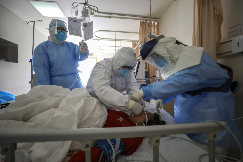 In this Sunday, Feb. 16, 2020, photo, medical workers provide treatment to a new coronavirus patient at a hospital in Wuhan in central China's Hubei province. Chinese authorities on Monday reported a slight upturn in new virus cases and hundred more deaths for a total of thousands since the outbreak began two months ago. (Chinatopix via AP)