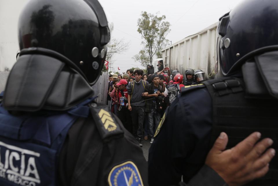 Riot police escort demonstrators during a protest over the 43 missing Ayotzinapa students, in Mexico City