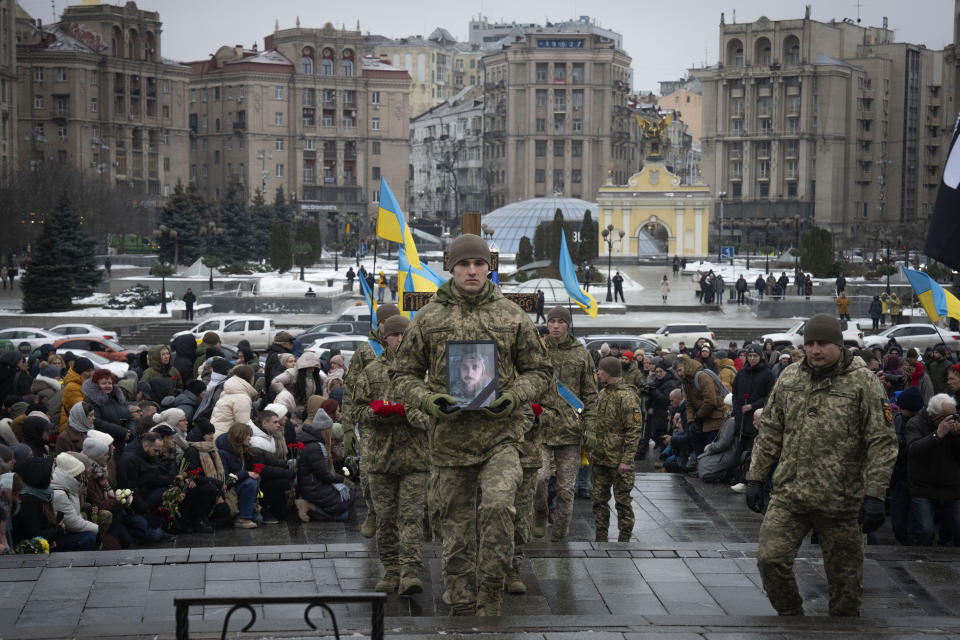 People kneel as soldiers carry the coffin of Ukrainian serviceman and famous Ukrainian poet Maksym Kryvtsov, who was killed in a battle with the Russian troops, during the funeral ceremony in St. Michael Cathedral in Kyiv, Ukraine, Thursday, Jan. 11, 2024. (AP Photo/Efrem Lukatsky)