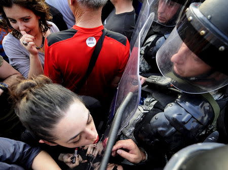 A girl puts lipstick and kisses the shield of the police in front of the Macedonian government building in Skopje, Macedonia May 5, 2015. Several thousand people protested in front of the building on Tuesday demanding the resignation of Prime Minister Nikola Gruevski, who was accused by the top opposition leader of trying to cover up the death of a 22-year-old who was beaten by a police member in 2011, local media reported. REUTERS/Ognen Teofilovski