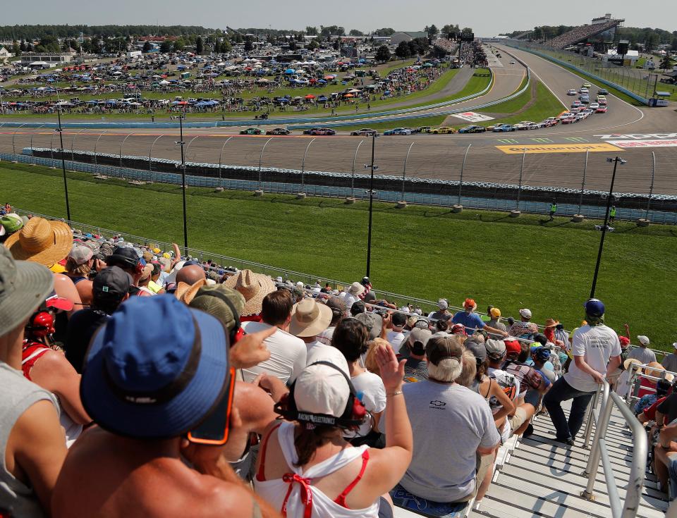 Spectators watch as drivers come around Turn 1 during a restart after a caution during a NASCAR Cup Series race at Watkins Glen International in 2018.