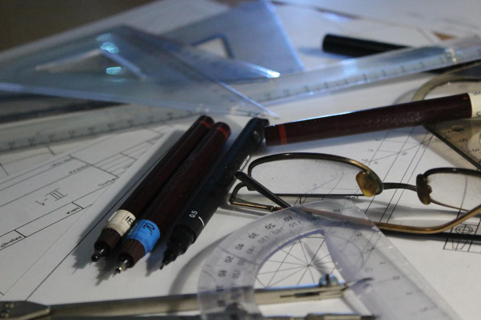 A person's desk with glasses, pens, documents
