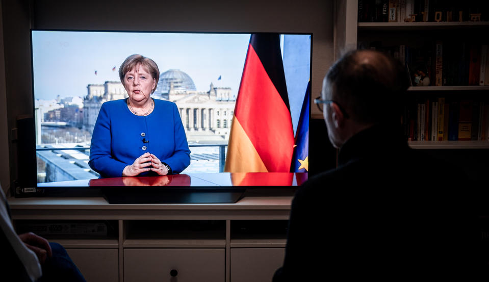 18 March 2020, North Rhine-Westphalia, Oberhausen: People watch the TV speech of the German Chancellor Angela Merkel (CDU) in a living room in Oberhausen. The Chancellor is talking about the coronavirus pandemic. Photo: Fabian Strauch/dpa (Photo by Fabian Strauch/picture alliance via Getty Images)