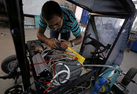 Islam Ibrahim, mechanical engineering student from Helwan University, checks electrical cables on the air-powered vehicle which he helped design to promote clean energy and battle increasing gas prices, in Cairo, Egypt August 7, 2018. Picture taken August 7, 2018. REUTERS/Mohamed Abd El Ghany