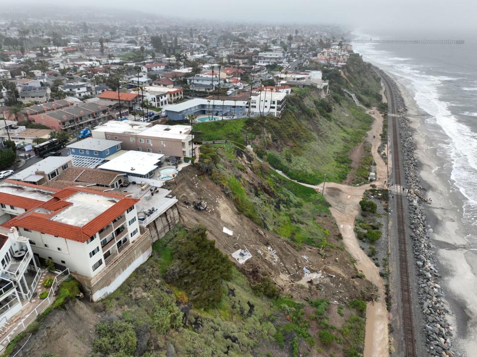 An aerial view of four cliff-side, ocean-view apartment buildings that were evacuated and tagged after heavy rains