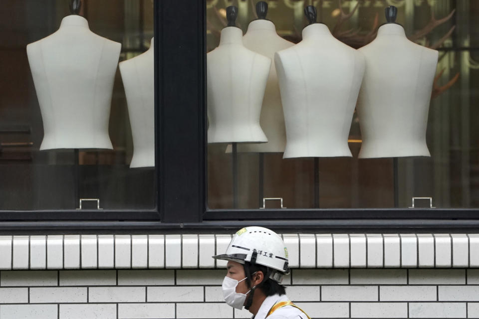 A construction worker wearing a protective mask to help curb the spread of the coronavirus walks past a clothing shop Monday, Nov. 2, 2020, in Tokyo. The Japanese capital confirmed more than 80 new coronavirus cases on Monday. (AP Photo/Eugene Hoshiko)