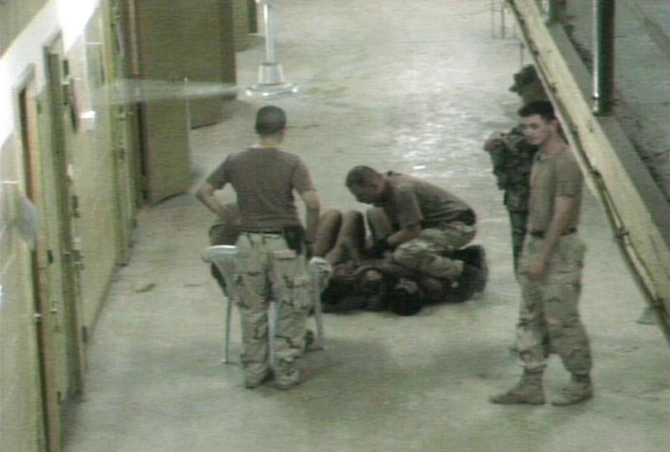 Iraqi detainees surrounded by US military personnel at Abu Ghraib prison