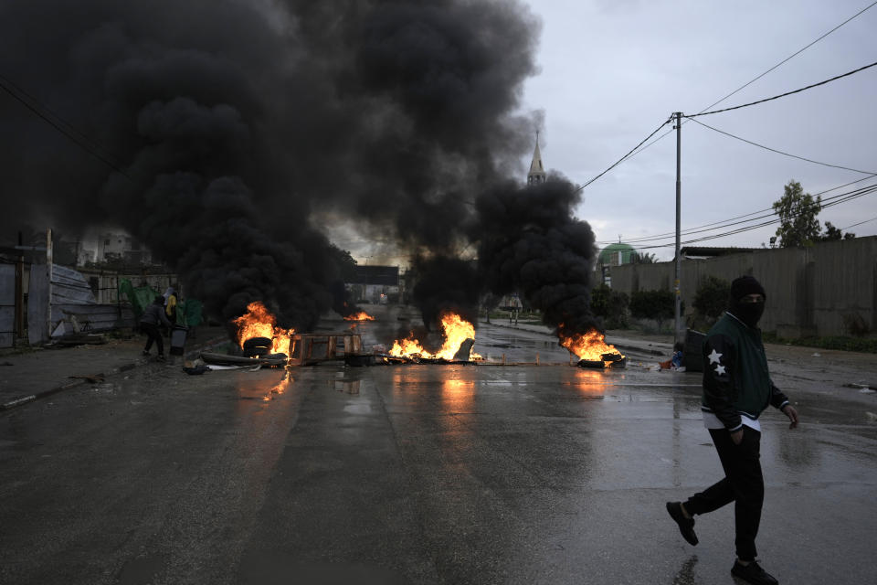 Tires burn as Palestinians clash with Israeli forces in Aqbat Jabr camp, southwest of the city of Jericho on Saturday, Feb. 4, 2023, during a search for the Palestinian suspects behind a shooting attack at a restaurant in a nearby settlement last week. The Israeli army raided the refugee camp near the Palestinian city of Jericho on Saturday, besieging houses it said were being used as hideouts for Palestinian attackers and shooting at residents who opened fire. (AP Photo/ Majdi Mohammed)