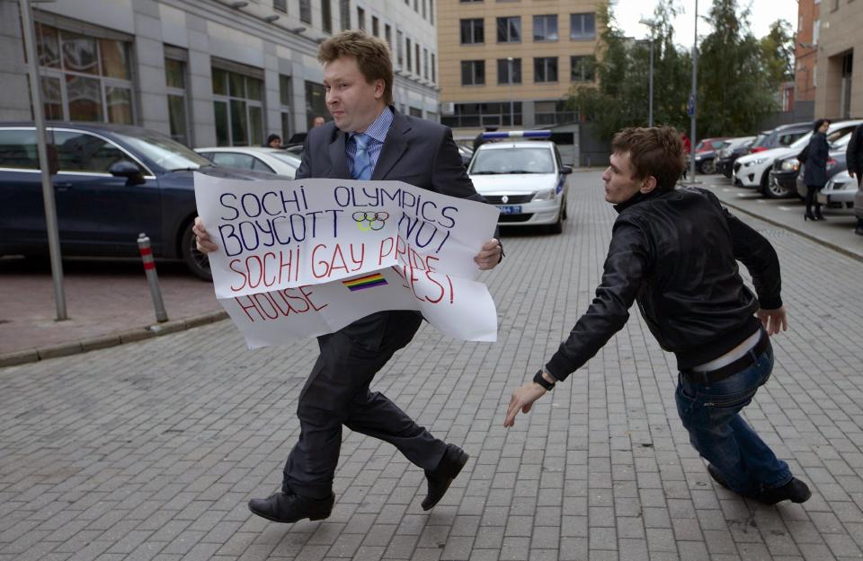 FILE - In this Wednesday, Sept. 25, 2013, file photo, Russia's leading gay rights campaigner Nikolai Alexeyev runs away from a plainclothes policeman during a protest outside the Sochi 2014 Winter Olympic Games organizing committee office, in downtown Moscow. When the Sochi Winter Olympics begin on Friday, Feb. 7, 2014, many will be watching to see whether Russia will enforce its law banning gay “propaganda” among minors if athletes, fans or activists wave rainbow flags or speak out in protest. The message so far has been confusing. (AP Photo/Ivan Sekretarev, file)