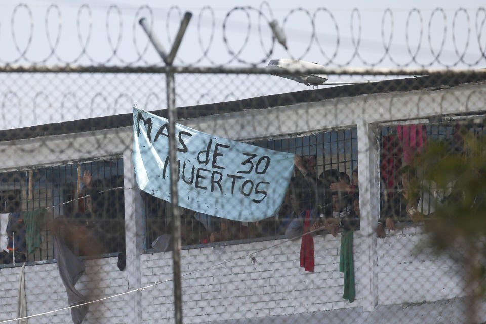 Inmates display a sign reading in Spanish "More than 30 dead" at La Modelo jail in Bogota, Colombia, Sunday, March 22, 2020. Violence broke out in the prison out of inmates' fears that authorities are not doing enough to prevent coronavirus inside overcrowded prisons. (AP Photo/Ivan Valencia)