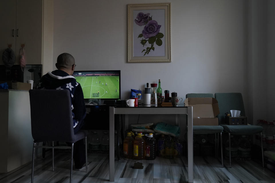 Wuhan resident Zhu Tao plays video game near supplies stocked under a table at home in Wuhan in central China's Hubei province on Wednesday, Oct. 21, 2020. Zhu, a government critic, took precautions against the virus early and felt vindicated when the outbreak exploded and the city went into lockdown. But now that the situation is back to something close to normal in Wuhan, Zhu finds himself at odds with his neighbors and the government. (AP Photo/Ng Han Guan)