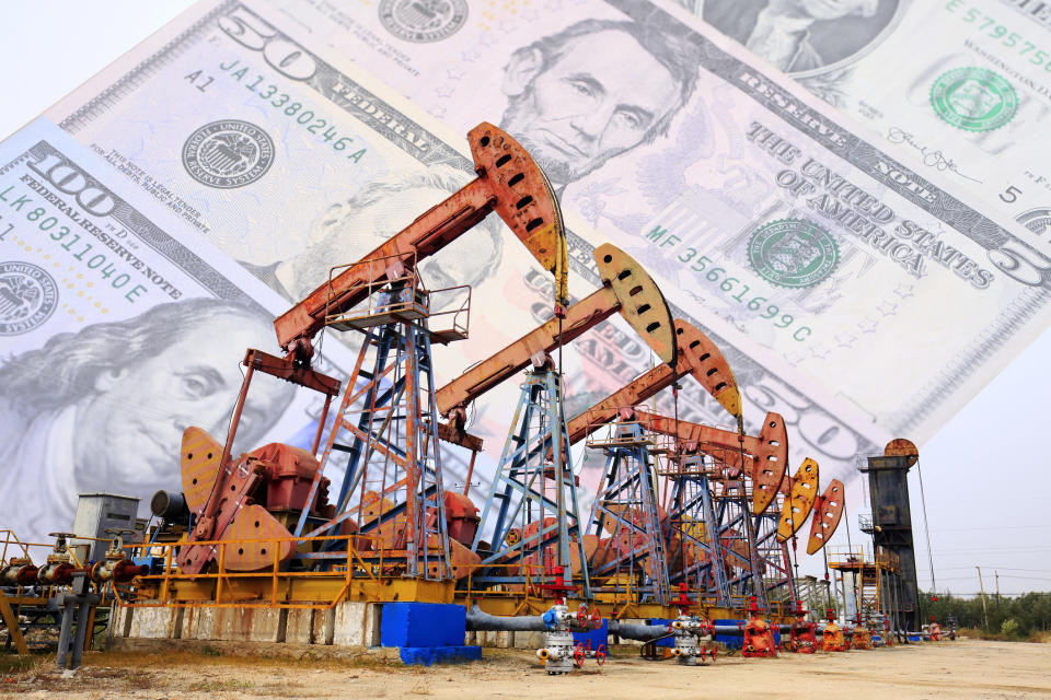 A row of oil pumps with cash in the background.