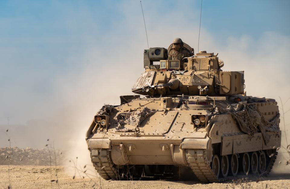 An infantry fighting vehicle driving on dusty ground.