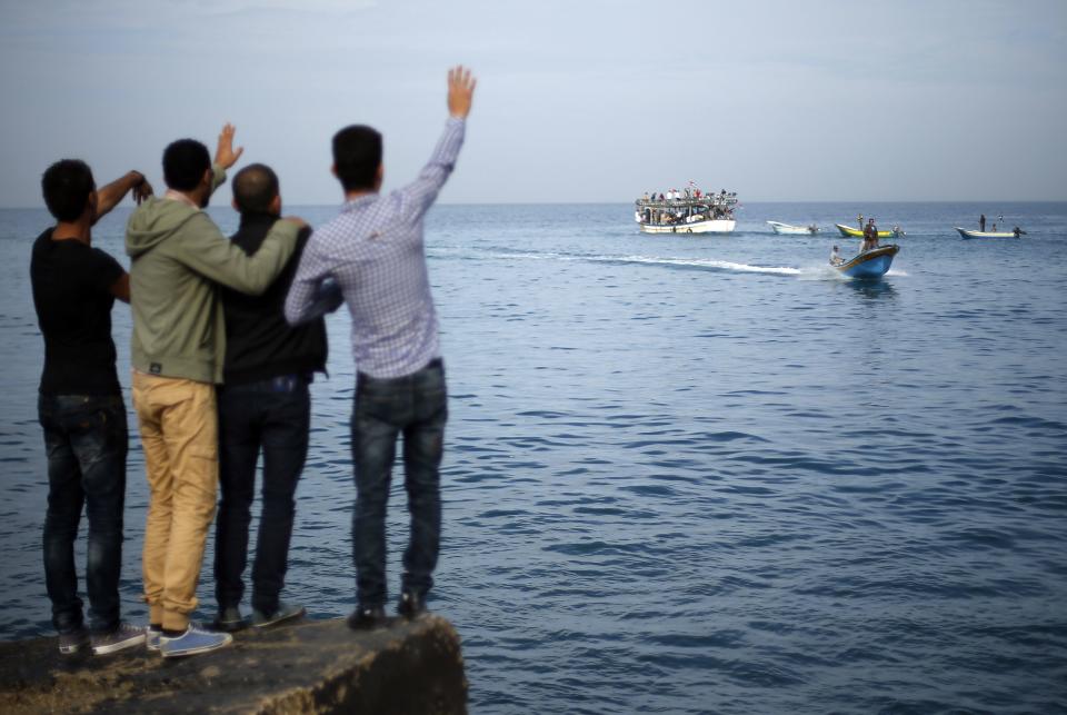 Palestinians wave to others on boats during a protest against the blockade on Gaza, at the seaport of Gaza City