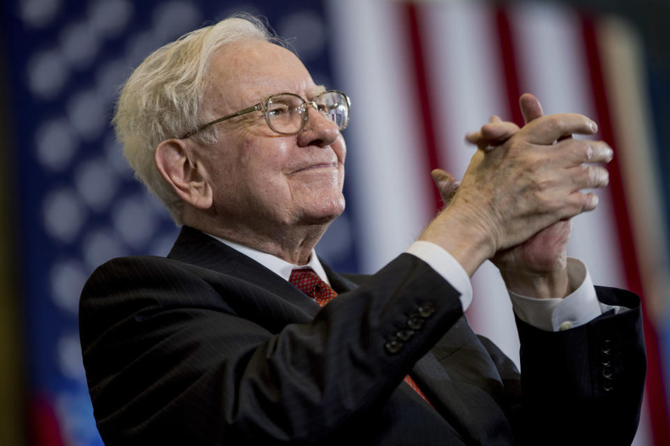 Berkshire Hathaway Chairman and CEO Warren Buffett claps his hands in front of an American flag.