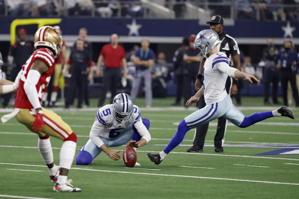 Dallas Cowboys punter Bryan Anger (5) holds as kicker Greg Zuerlein, right, kicks a field goal under pressure from the San Franciso 49ers defense in the second half of an NFL wild-card playoff football game in Arlington, Texas, Sunday, Jan. 16, 2022. (AP Photo/Ron Jenkins)