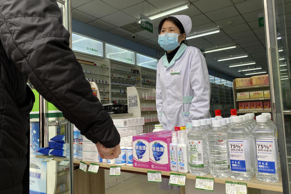 Una farmacéutica atiende a clientes en la entrada de una tienda en Beijing, China, el 20 de febrero de 2020. (AP Foto/Ng Han Guan)