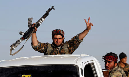 A fighter of Syrian Democratic Forces makes the V-sign and raises his rifle as their convoy passes in Ain Issa, Syria October 16, 2017. REUTERS/Erik De Castro